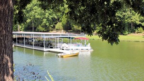 A docked boat at a marina with a covered seating area and a small yellow boat nearby.