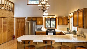 Una cocina con gabinetes de madera, un refrigerador de acero inoxidable, un microondas, una estufa y una isla grande con taburetes de bar.