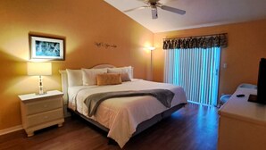 A bedroom with a bed, nightstand, lamp, and a ceiling fan.