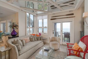 A spacious living room with a large window, a sofa, a glass coffee table, and a red chair.
