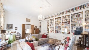 A spacious living room with a large bookshelf, a sofa, a coffee table, and a chandelier.