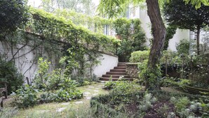 A lush garden with a stone staircase leading up to a white building.