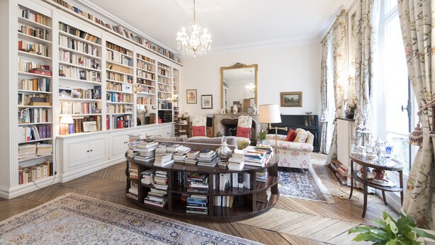 A spacious library with bookshelves, a fireplace, and a round coffee table.