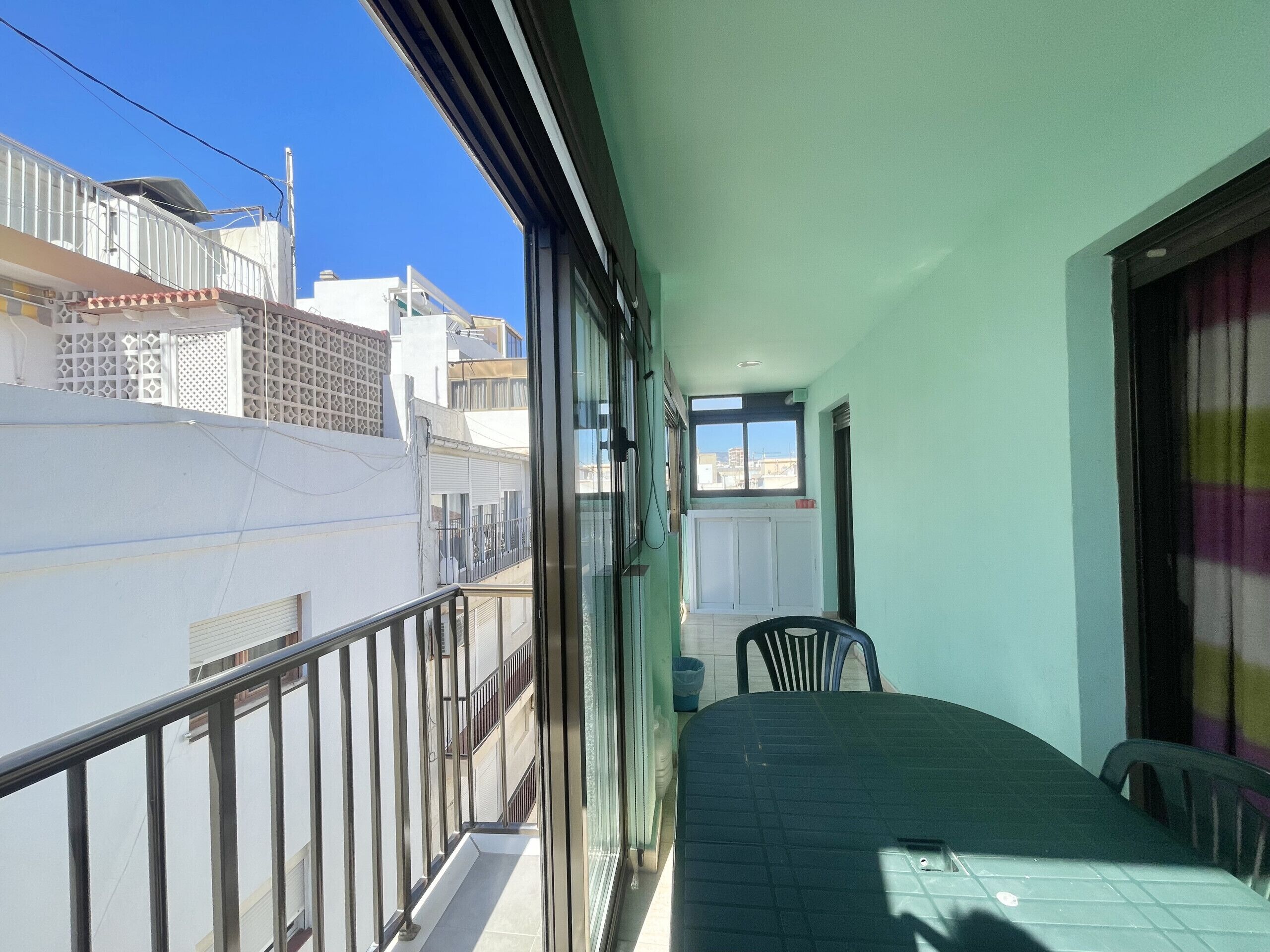 Un balcon donnant sur les immeubles voisins, une fenêtre avec vue et une chaise.