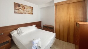 Ein Hotelzimmer mit einem Bettgestell aus Holz, weißen Bettwäsche, einem Bild an der Wand und einem Holzschrank.