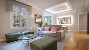 Een moderne woonkamer met een bank, een voetenbankje en een glazen salontafel.