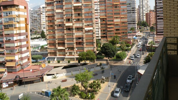 A high-rise residential building with multiple balconies, a street with cars, and a clear sky. - PRINCIPADO CENTRO (4 BEDROOMS) (Benidorm)