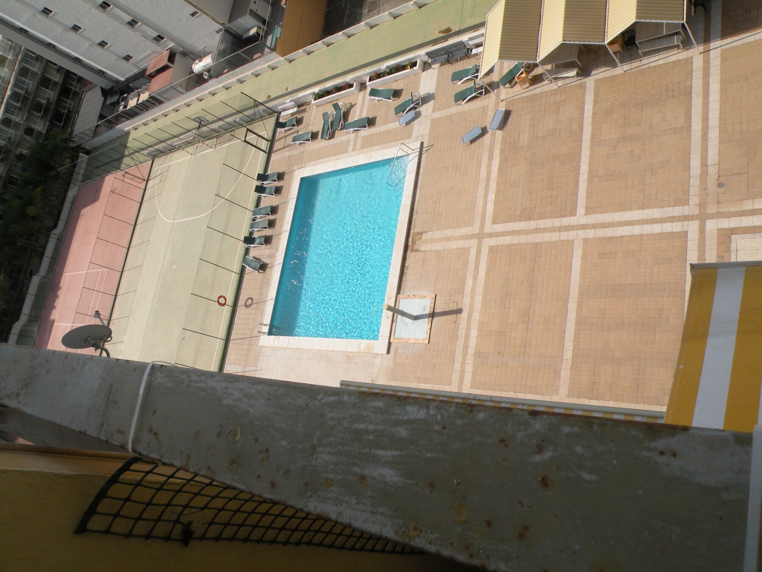 Piscina no terraço com espreguiçadeiras e antena parabólica.