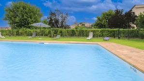 A swimming pool with lounge chairs and an umbrella, surrounded by greenery and a clear sky. - Recently restored stone villa with private pool, ideal for couples of friends or families wishing to (Castiglion Fiorentino)