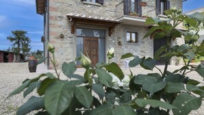 A stone building with a wooden door, windows, and a balcony with potted plants. - Recently restored stone villa with private pool, ideal for couples of friends or families wishing to (Castiglion Fiorentino)