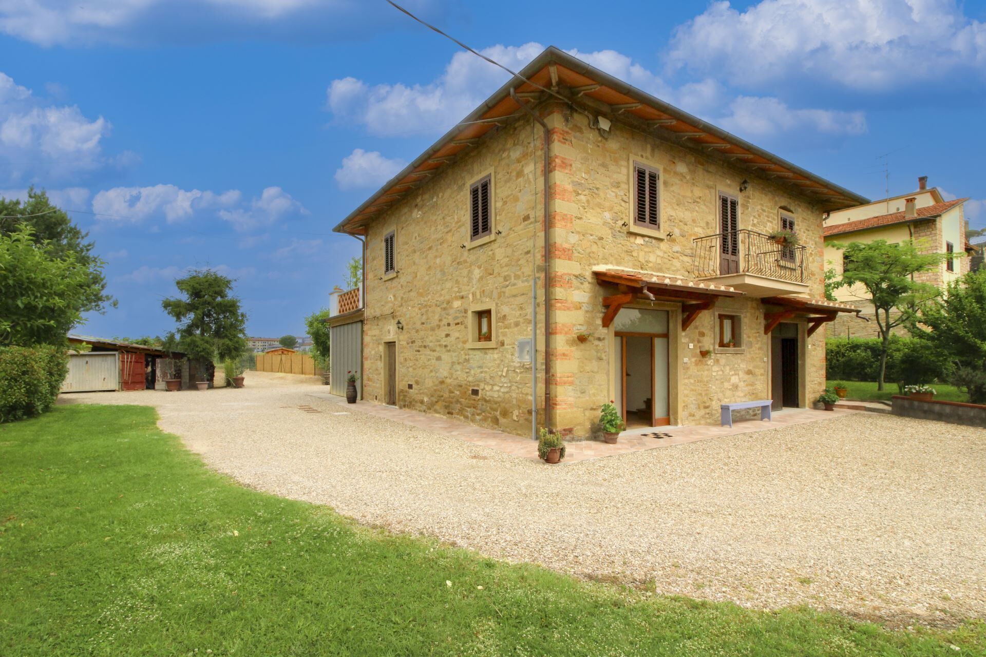 A stone house with a gravel driveway and a small lawn.