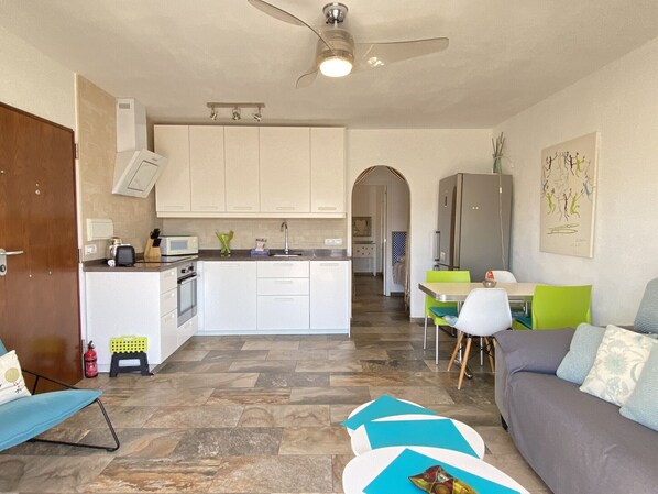 A compact living space with a kitchenette, a dining area, and a seating area with a sofa and chairs. - Litoral Burriana Apartment by Casasol (Nerja)