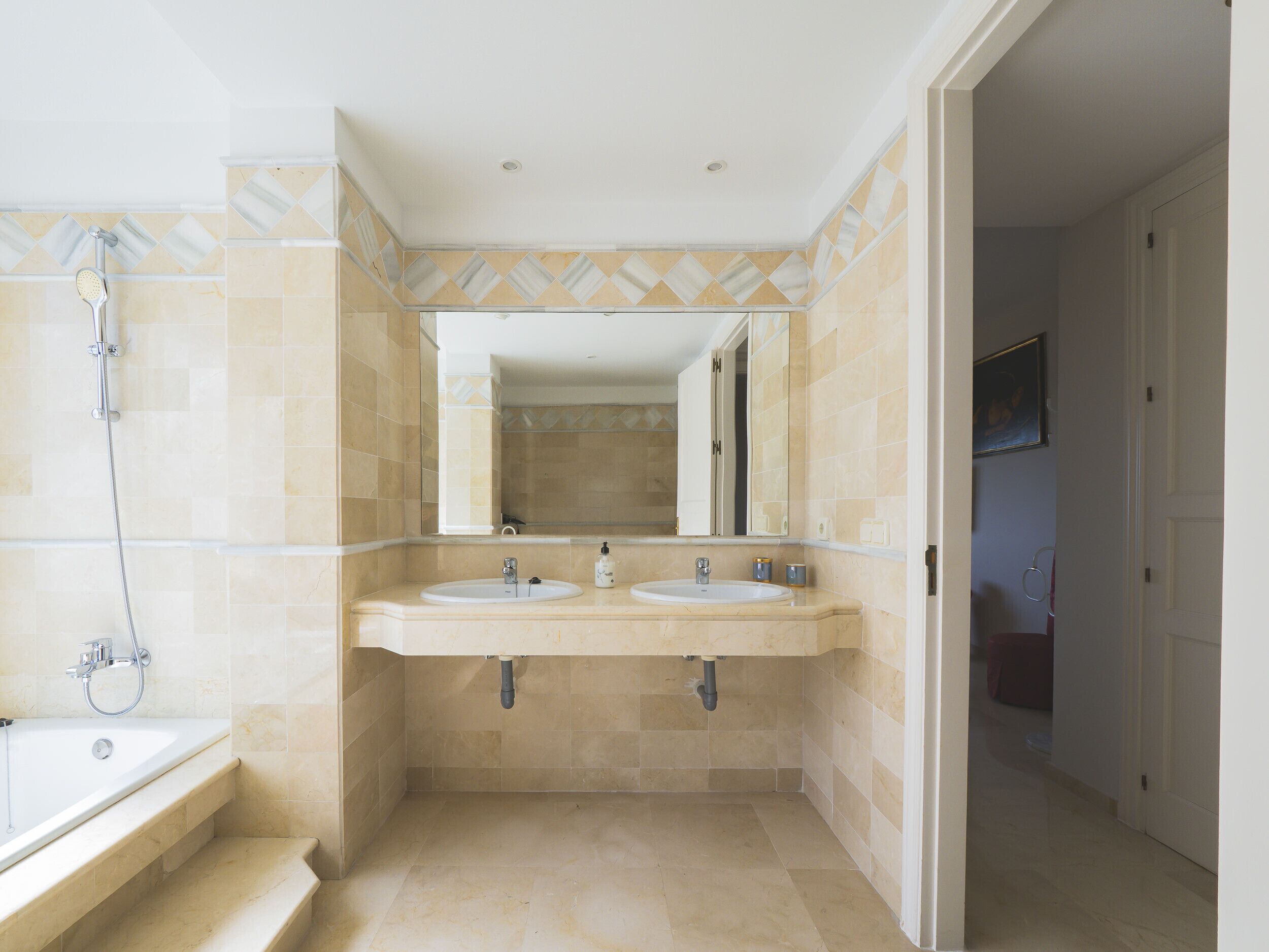 A bathroom with two sinks, a shower, and a large mirror.