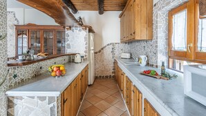 A kitchen with stone walls, wooden cabinets, and a tiled floor. - Villa La Pace, Charming 3 bedroom villa with private pool with views of Amalfi Coast (Sant'Agnello)