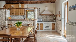 A rustic kitchen with stone walls, wooden cabinets, and a tiled floor. - Villa La Pace, Charming 3 bedroom villa with private pool with views of Amalfi Coast (Sant'Agnello)