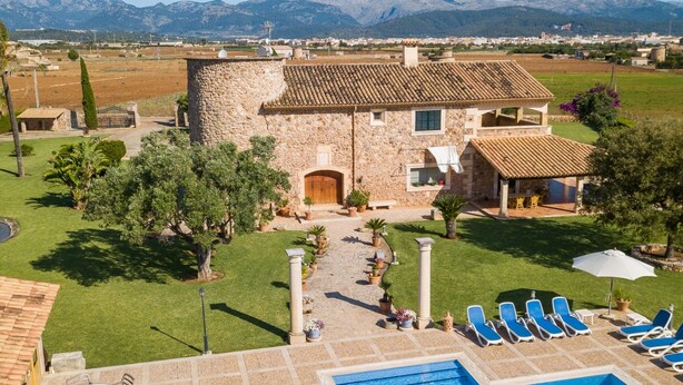 Una villa de piedra con piscina, mobiliario exterior y vistas a montañas.