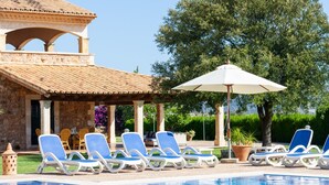 Zona de piscina con sillones de descanso y una pérgola.