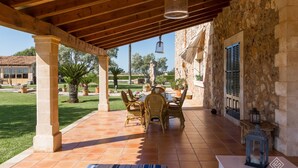 Un patio cubierto con un muro de piedra, vigas de madera y suelo de baldosas.