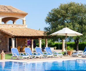 Ein Poolbereich mit Liegestühlen und einer Pergola.