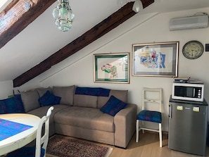 A cozy living space with a sofa, a small table, a microwave, and a framed picture on the wall. - Venice Center apartment near Rialto bridge (Venezia)