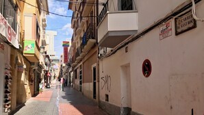 A narrow street lined with buildings, some with signs indicating businesses like a pizzeria and a restaurant. - SAN ROC APARTMENT R035 (Benidorm)