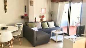 A living room with a grey sofa, white chairs, a small white table, and a TV on a white stand. - SAN ROC APARTMENT R035 (Benidorm)