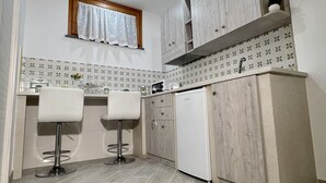 Una cocina compacta con dos taburetes de bar, un microondas integrado y un refrigerador.