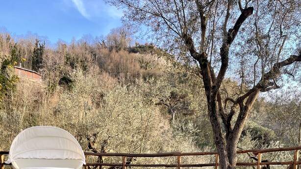 Una piscina cristalina con cubierta de madera y un área de estar exterior blanca.