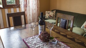 A wooden table with a wine bottle, two glasses, and a decorative flower centerpiece.