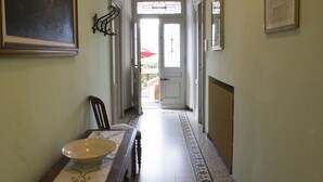 A hallway with a dining table set with a bowl and a chair, a radiator, and framed pictures on the walls.