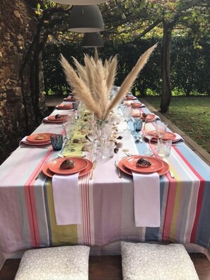 Enjoy a serene outdoor dining experience in our garden setting, surrounded by trees and a stone wall.