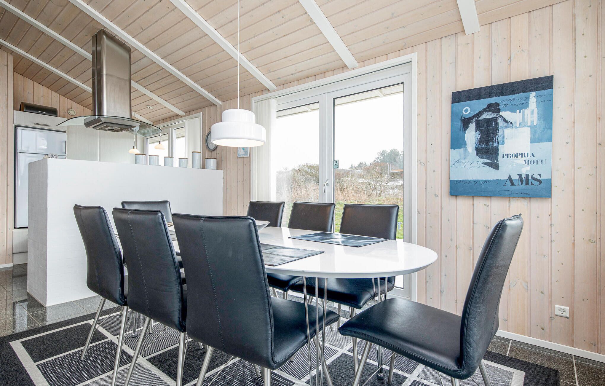 A modern kitchen with a white countertop, stainless steel appliances, and a hanging light fixture.