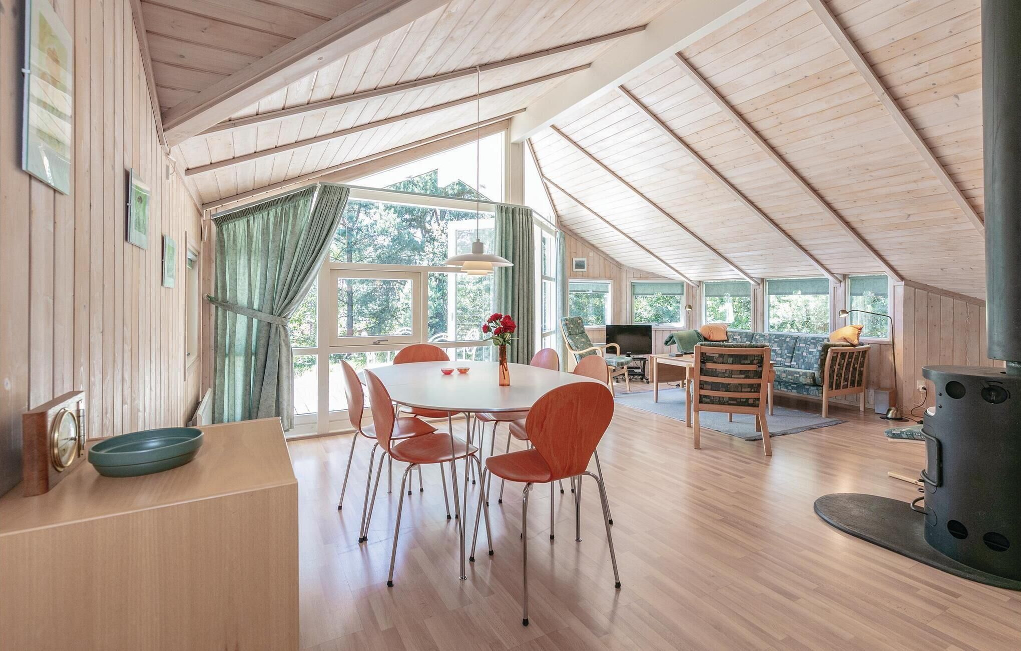 A spacious dining area with a wooden table and chairs, large windows, and a modern stove.