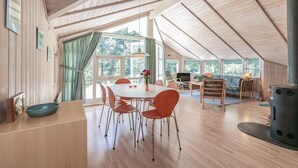 A spacious dining area with a wooden table and chairs, large windows, and a modern stove. - Gorgeous home in Aakirkeby (Aakirkeby)