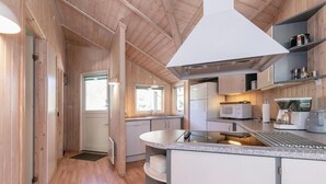 A modern kitchen with wooden walls, a central island, and built-in appliances. - Gorgeous home in Aakirkeby (Aakirkeby)