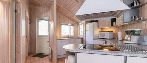 Una cocina moderna con paredes de madera, una isla central y electrodomésticos integrados.