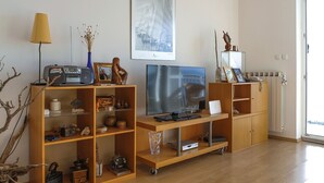Un salon comprenant un meuble de rangement en bois pour l’équipement audiovisuel, un téléviseur et divers objets décoratifs.