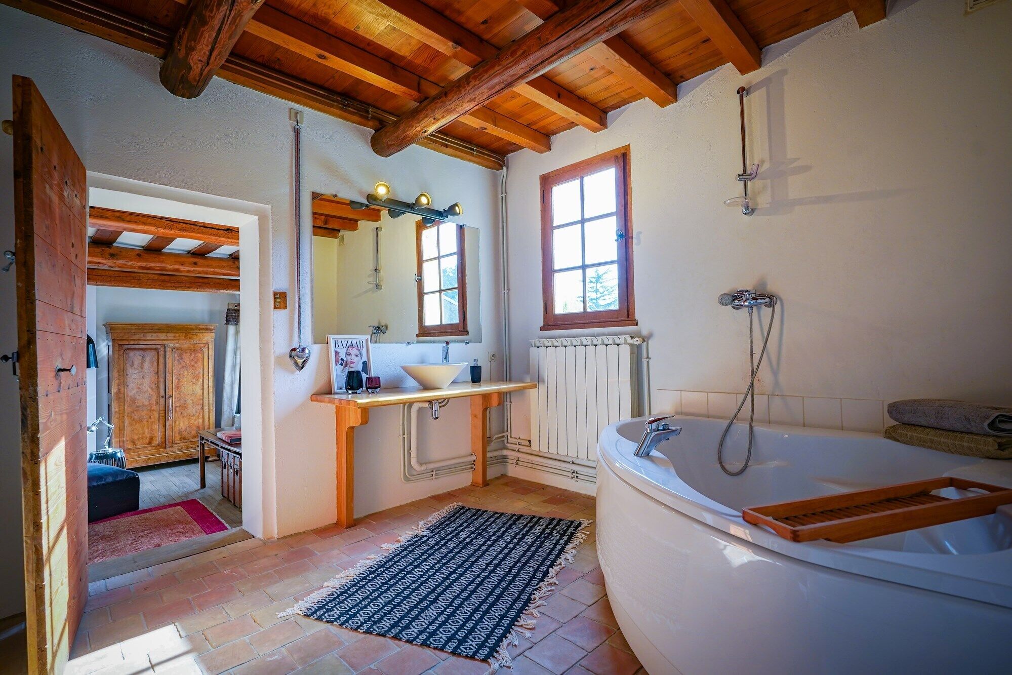 Une salle de bain avec un plafond en bois, une baignoire, un lavabo et une fenêtre.