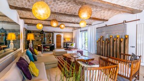 Ein geräumiges Wohnzimmer mit einer Sofagarnitur, Holzstühlen und hängenden, kugelförmigen Lampen.