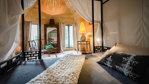 Ein Schlafzimmer mit einem Bett, einer Bank, einer Lampe und einem Sessel.