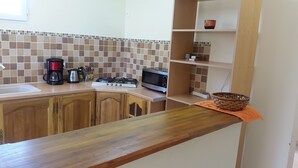 Una cocina con armarios de madera, estufa a gas, cafetera y microondas.