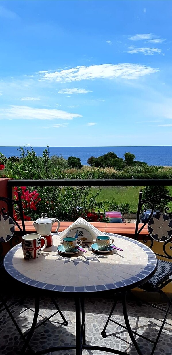 A round table with a view of the sea, a chair, and a metal railing.