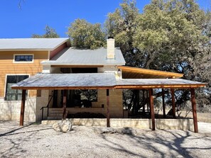 A modern house with a covered patio, stone foundation, and a large tree in the background. - Porter's Tree Haus, Private Riverfront @Vacation Frio River Sleeps 28-32 (Concan)