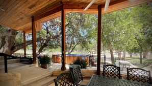A covered outdoor seating area with a wooden ceiling, metal chairs, and a table.