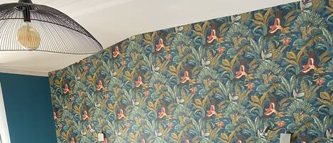 A bedroom with a large bed, two bedside lamps, and a patterned wallpaper.