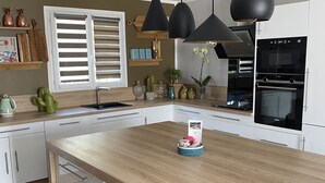 Una cocina moderna con una isla central, armarios blancos e iluminación colgante negra.