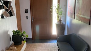 Un salón moderno con suelo de madera, un sillón gris, una planta en maceta y arte abstracto en la pared.