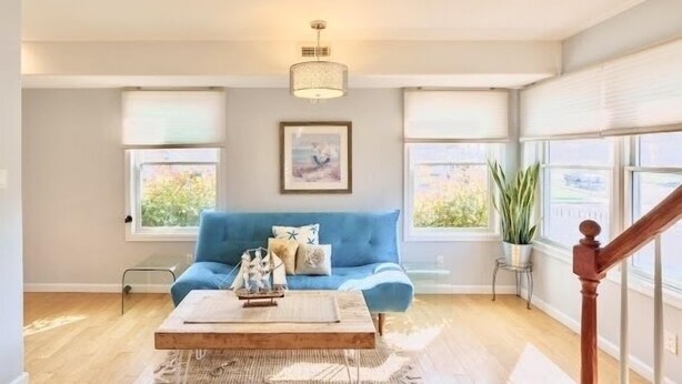 Un salon avec un canapé bleu, une table basse en bois et un luminaire suspendu.