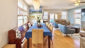 Une salle à manger spacieuse avec une longue table, des sièges confortables et un lustre.
