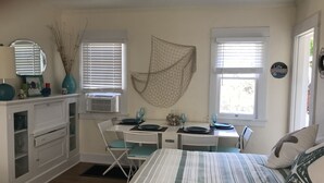 A bedroom with a bed, a desk, and a chair. There are two windows with blinds, a dresser, and a wall-mounted shelf. - LARGE STUDIO, IN GREAT NEIGHBORHOOD,PET FRIENDLY, PLENTY OF PARKING (Long Beach)